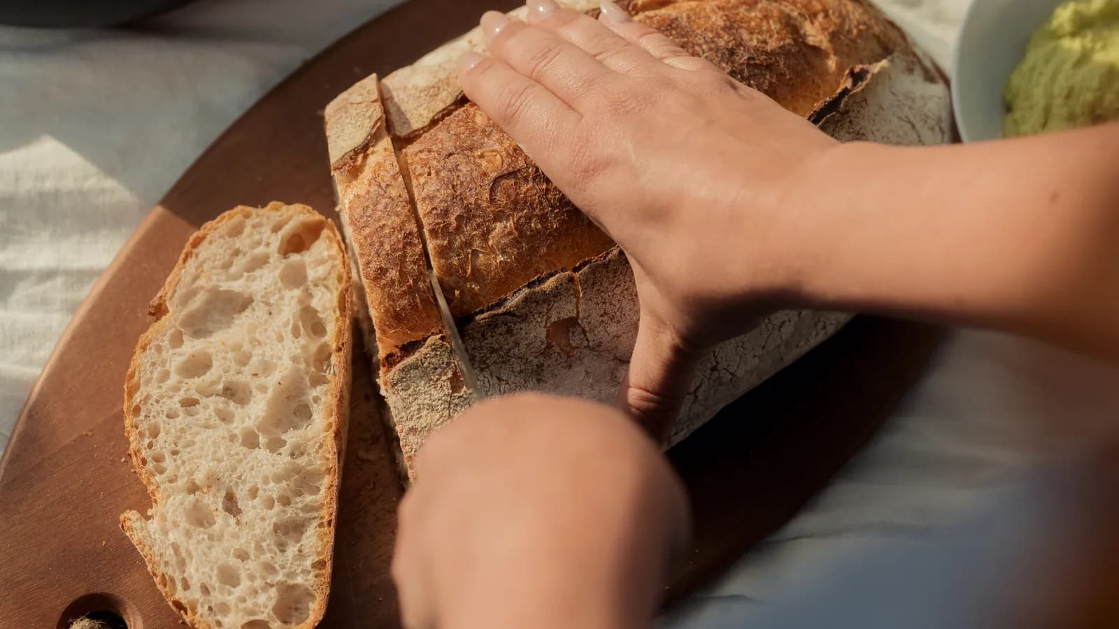 Krojenie chleba na zastawionym stole z sałatką